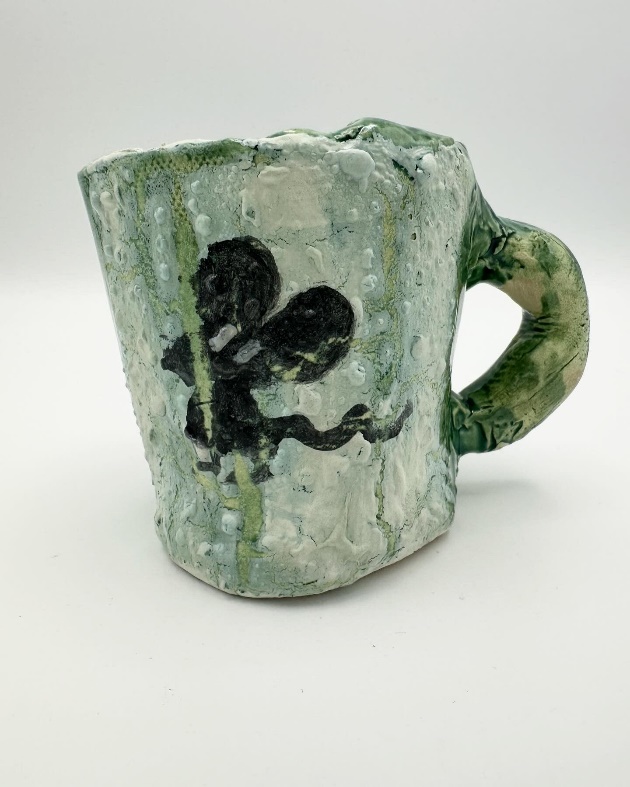 A green and white mug with a black designDescription automatically generated